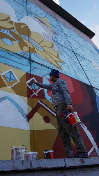 Художник Erendaj Никита красит фасад в Шерегеше на улице Держинского, 33